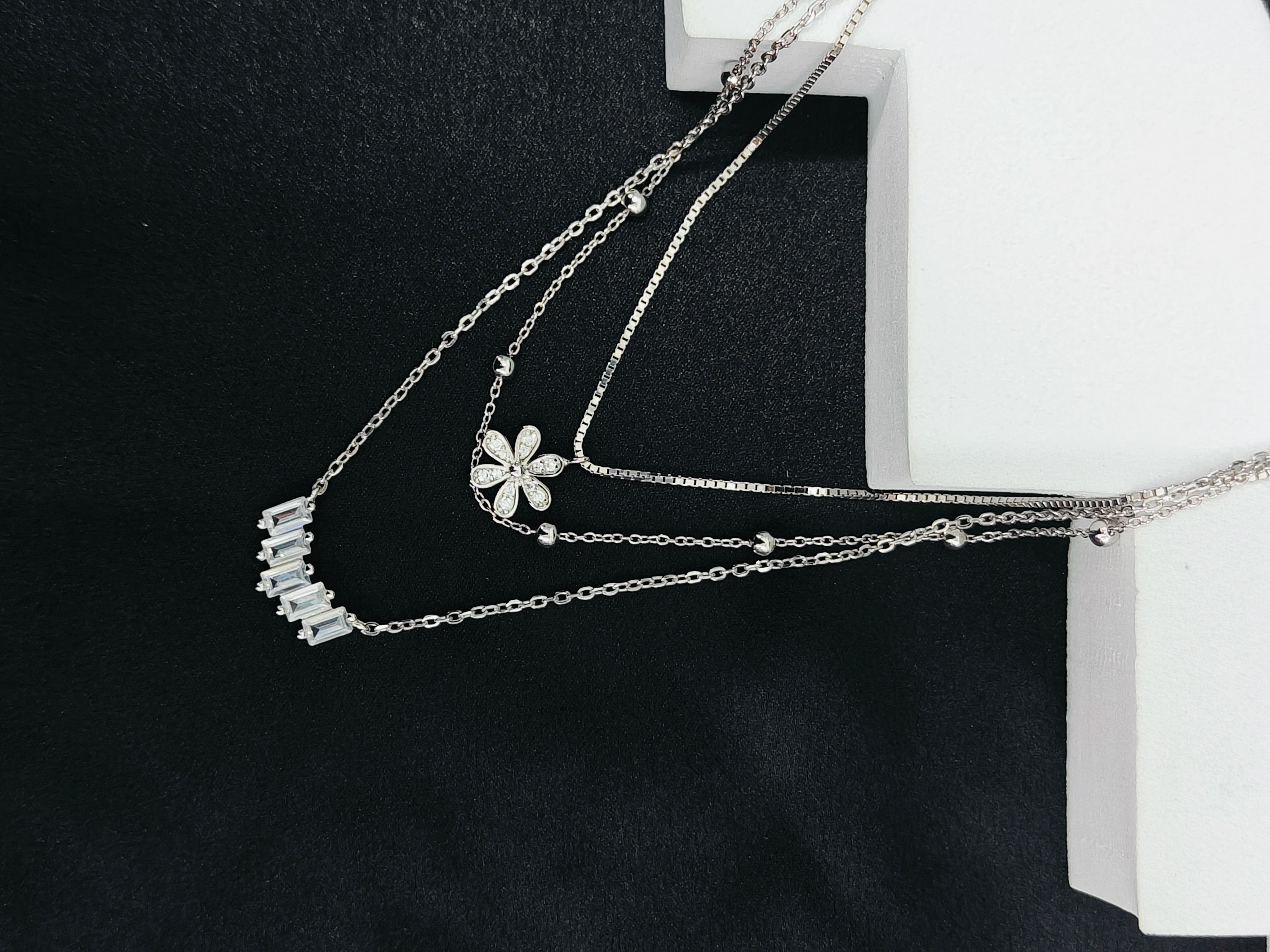 Silver necklace with floral pendant on a black background